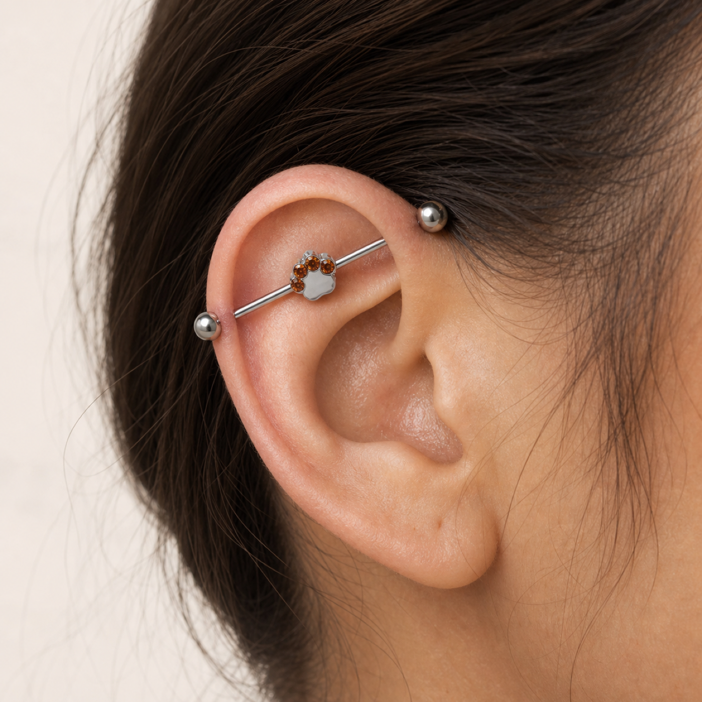 G23 Titanium Cat Paw Crystal Industrial Barbell Earring worn on ear in clean window daylight