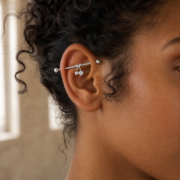 G23 Titanium Cherry Crystal Industrial Barbell Earring in Silver worn on ear in clean window daylight