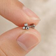 Titanium Stud Earrings Tridot for Sensitive Ears shown at fingertip scale
