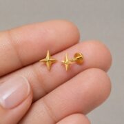 Flat Back Stud Earrings Twinkle Star in F136 Titanium shown at fingertip scale