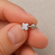 Flat Back Stud Earrings Tiny Four-Petal in F136 Titanium shown at fingertip scale