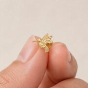 Flat Back Stud Earrings Hummingbird in F136 Titanium shown at fingertip scale