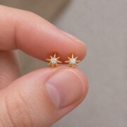Flat Back Stud Earrings Crystal Starburst in F136 Titanium shown at fingertip scale