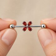 G23 Titanium Four-Petal Crystal Industrial Barbell Earring shown at fingertip scale