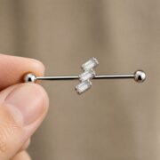 G23 Titanium Three Baguette Industrial Barbell Earring in Natural Titanium shown at fingertip scale
