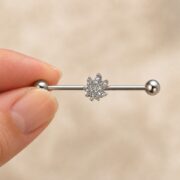 G23 Titanium Maple Leaf Crystal Industrial Barbell Earring in Natural Titanium shown at fingertip scale