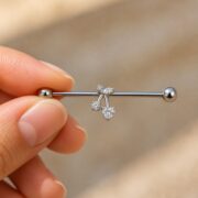 G23 Titanium Cherry Crystal Industrial Barbell Earring in Natural Titanium shown at fingertip scale
