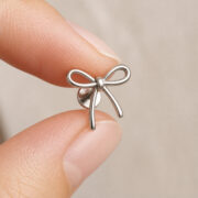 Titanium Flat Back Earrings – Outline Bow Cartilage Stud - fingertip scale view