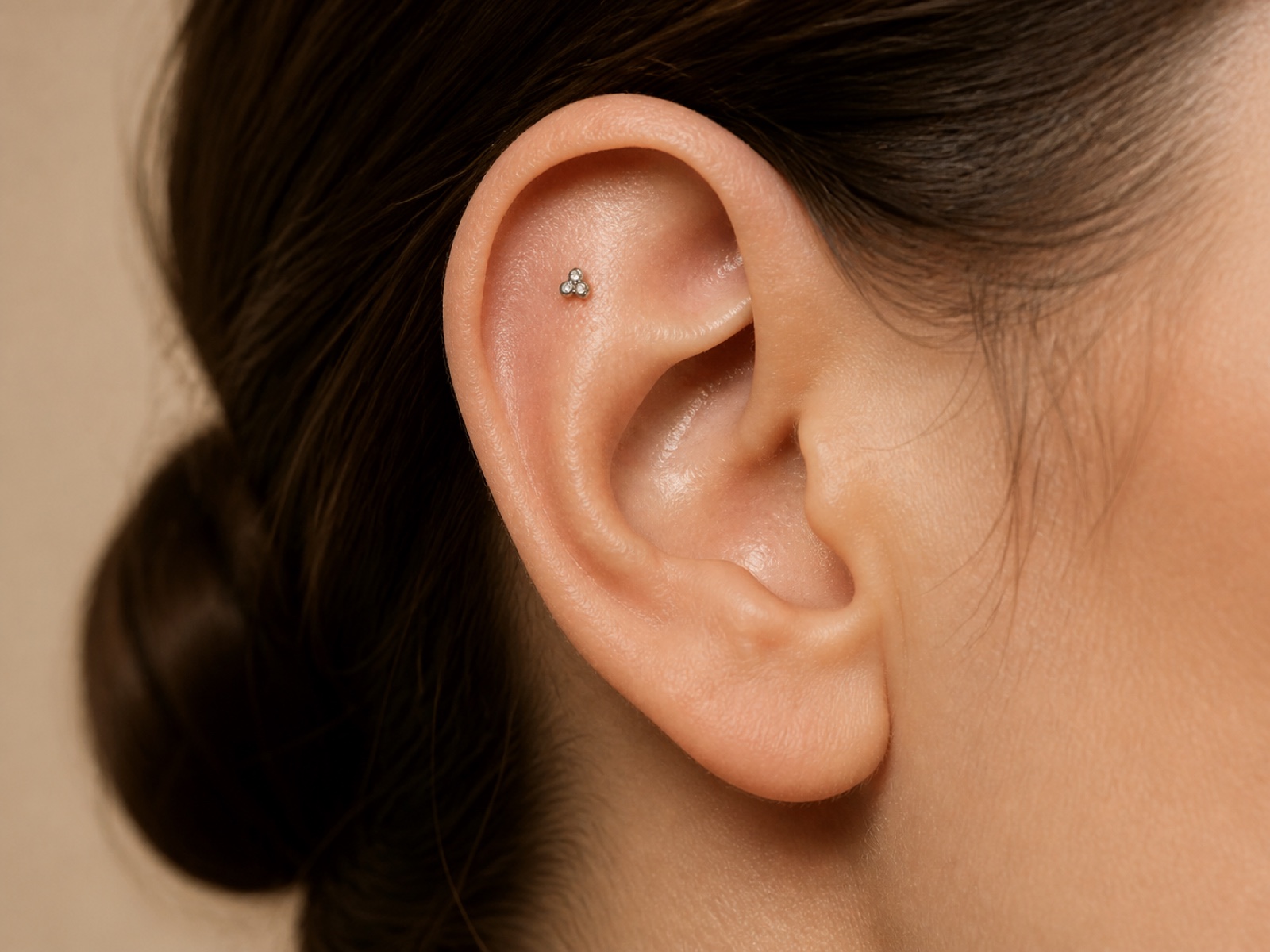 close-up of a healthy ear wearing a small titanium stud in the upper flat piercing area