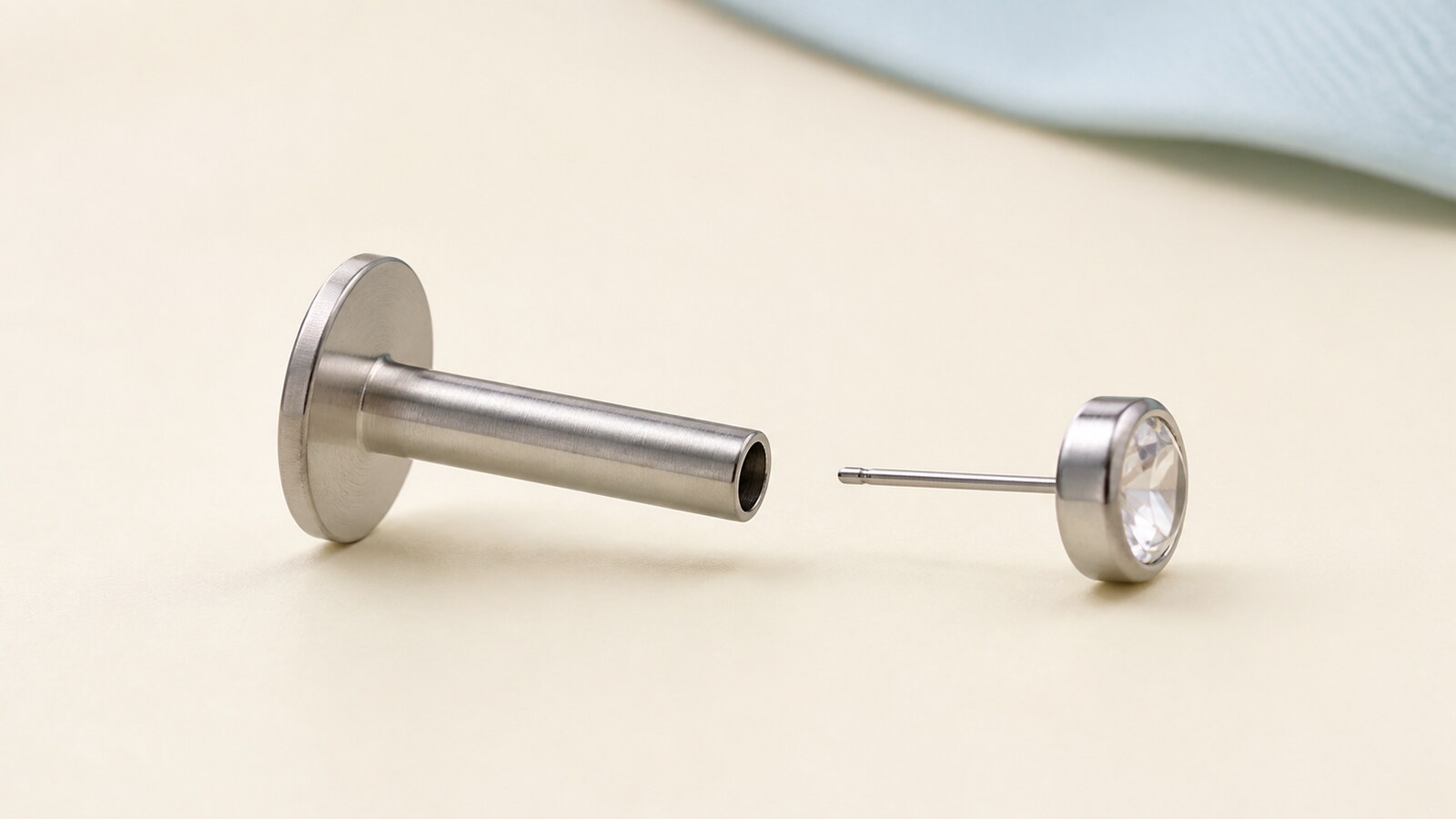 Disassembled titanium flat-back stud showing one hollow post with a fixed disk and one threadless front