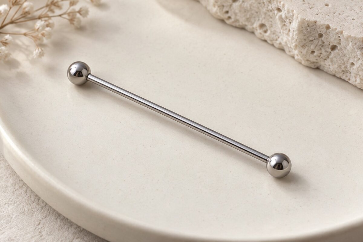 A long straight silver-colored barbell with two round ends on an ivory surface.