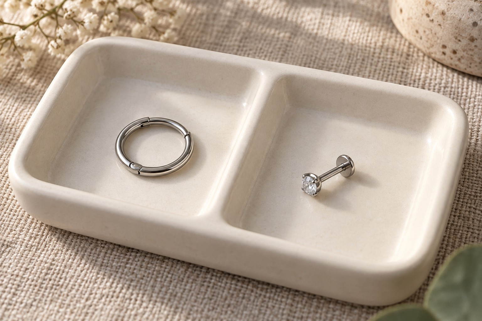 A silver-colored ring and a clear-stone flat-back stud in separate tray compartments.