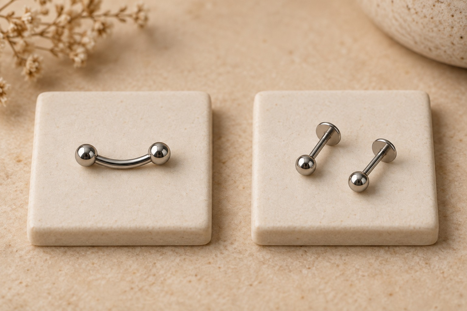 A curved barbell on one tile and two separate straight flat-back studs on another.