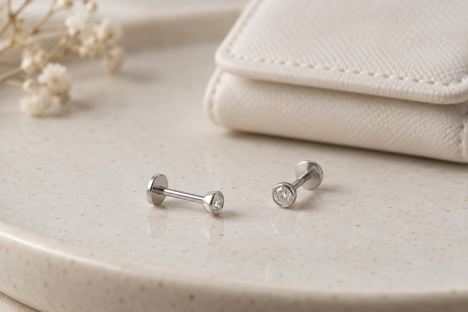 Two clear-stone flat-back studs showing their short posts and rear disks.