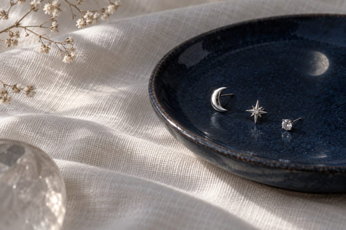 Crescent, star and crystal studs on a dark blue dish beside ivory linen.