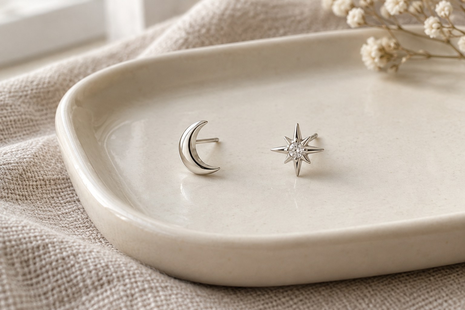 One crescent stud and one pointed star stud on an ivory tray.