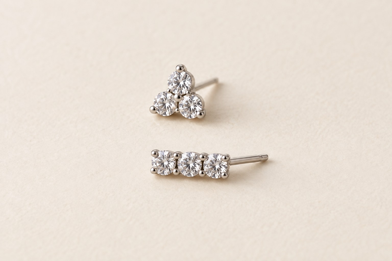 A small crystal cluster and an elongated three-stone bar stud lying separately.