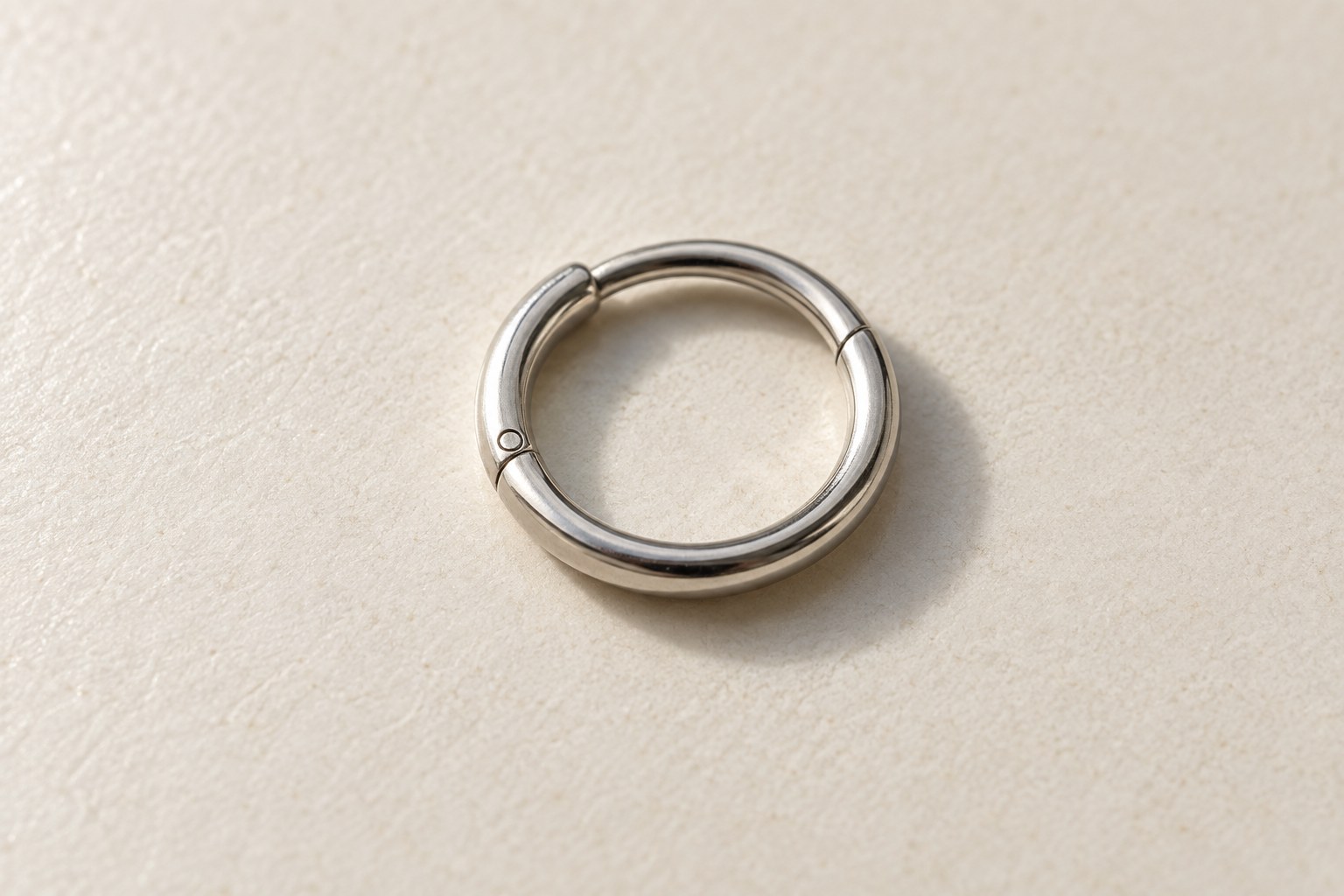 A small silver-tone clicker hoop resting on a pale surface.
