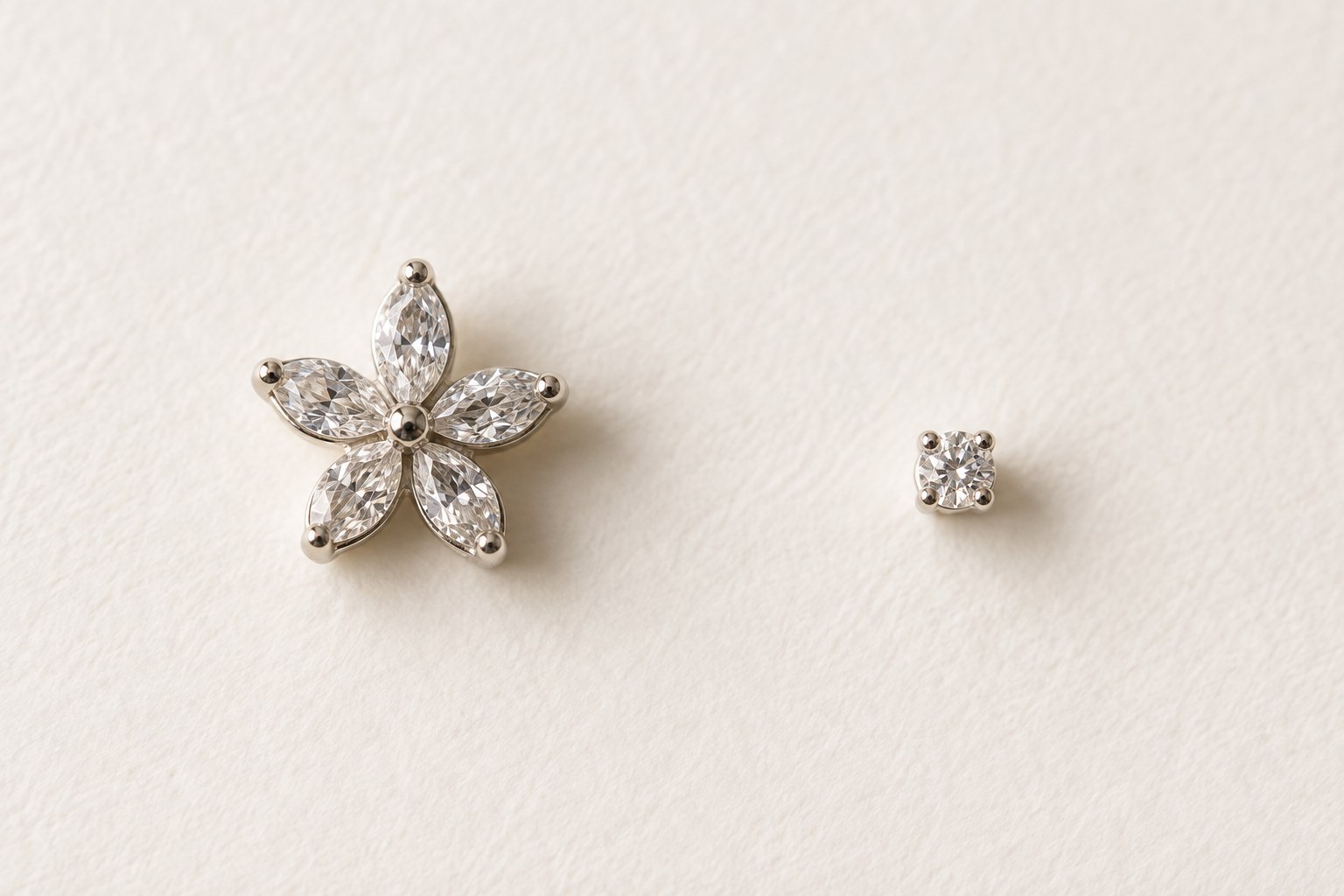 A five-petal crystal flower stud beside a small round crystal stud on ivory paper.