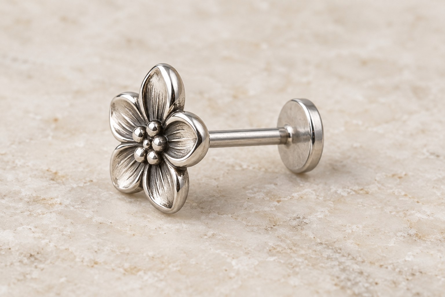 A flower-front earring viewed from the side with a short post and flat rear disk.