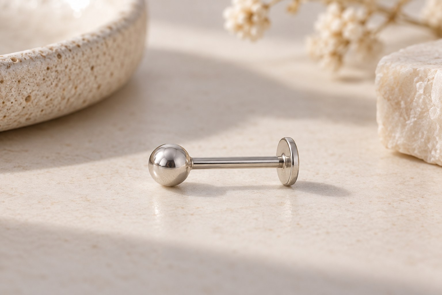 A silver-toned ball stud lying on its side with a straight post and flat rear disc.