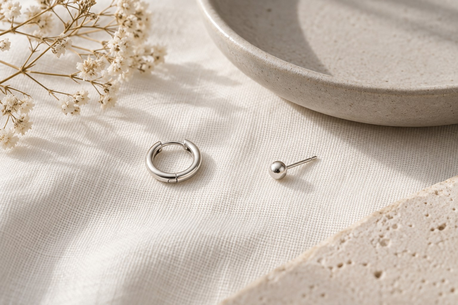 A small hoop earring beside a round ball stud on a plain surface.