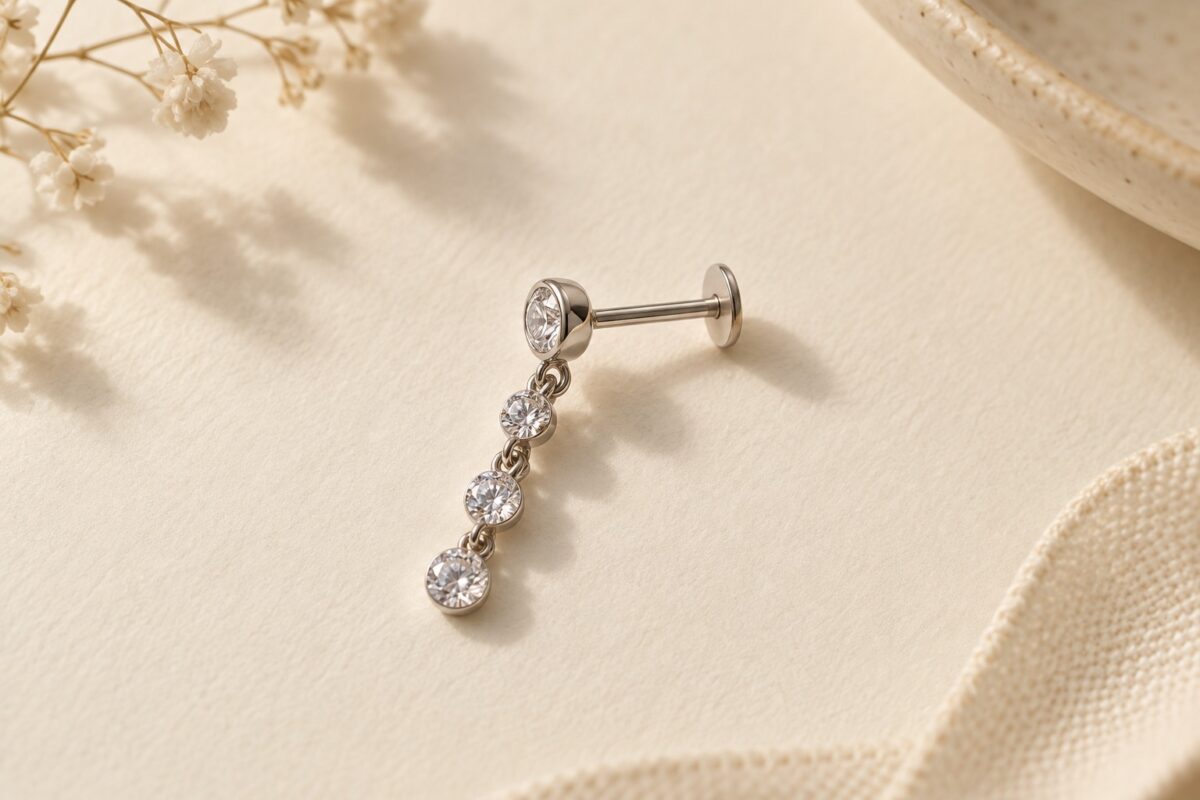 A straight flat-back stud with a short linked crystal drop on ivory paper.