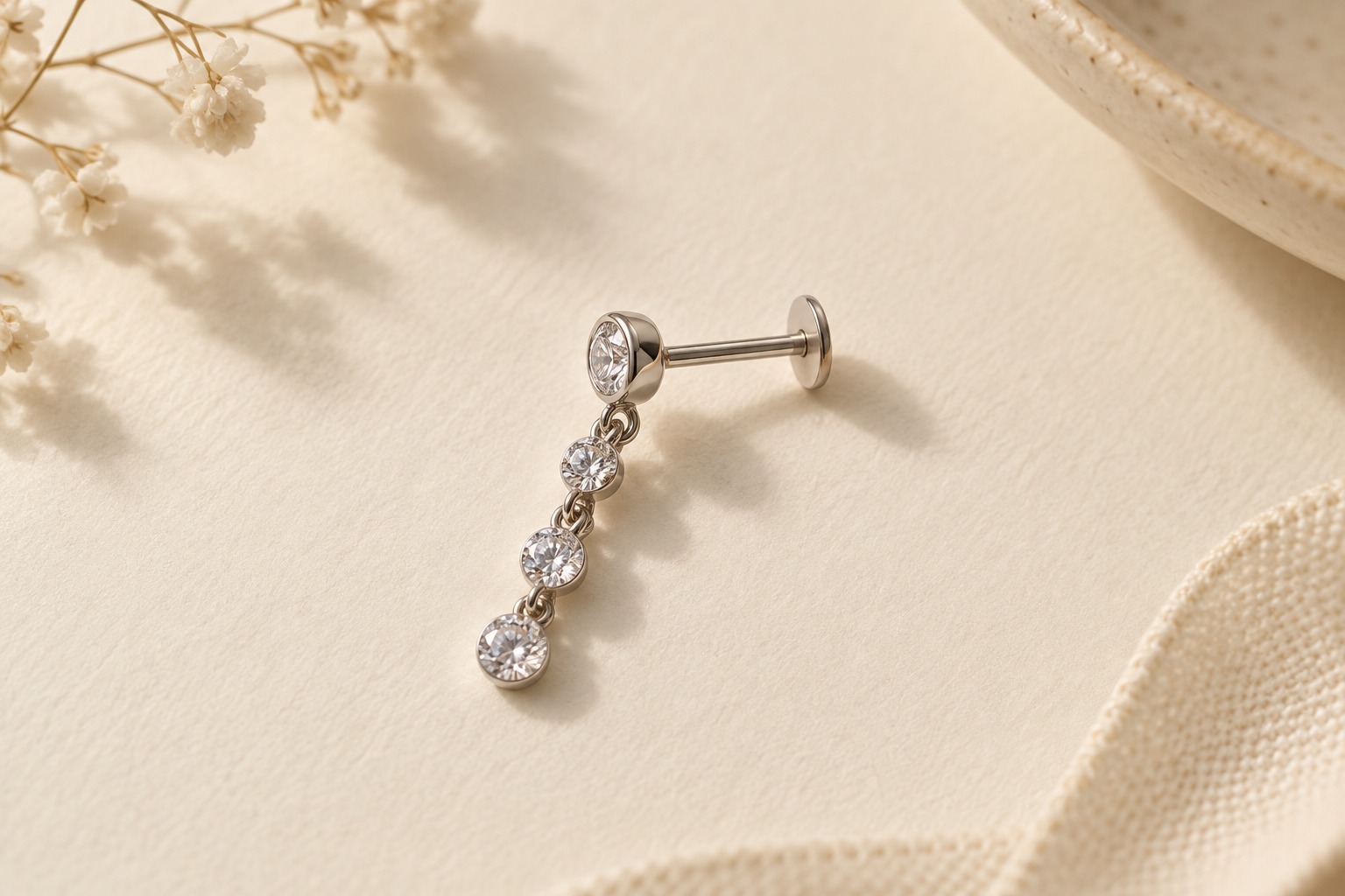 A straight flat-back stud with a short linked crystal drop on ivory paper.
