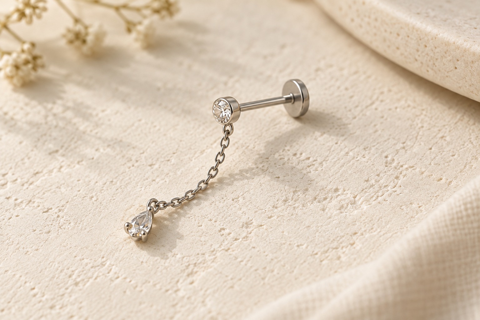 A flat-back stud with a fine chain and clear teardrop hanging from the front.