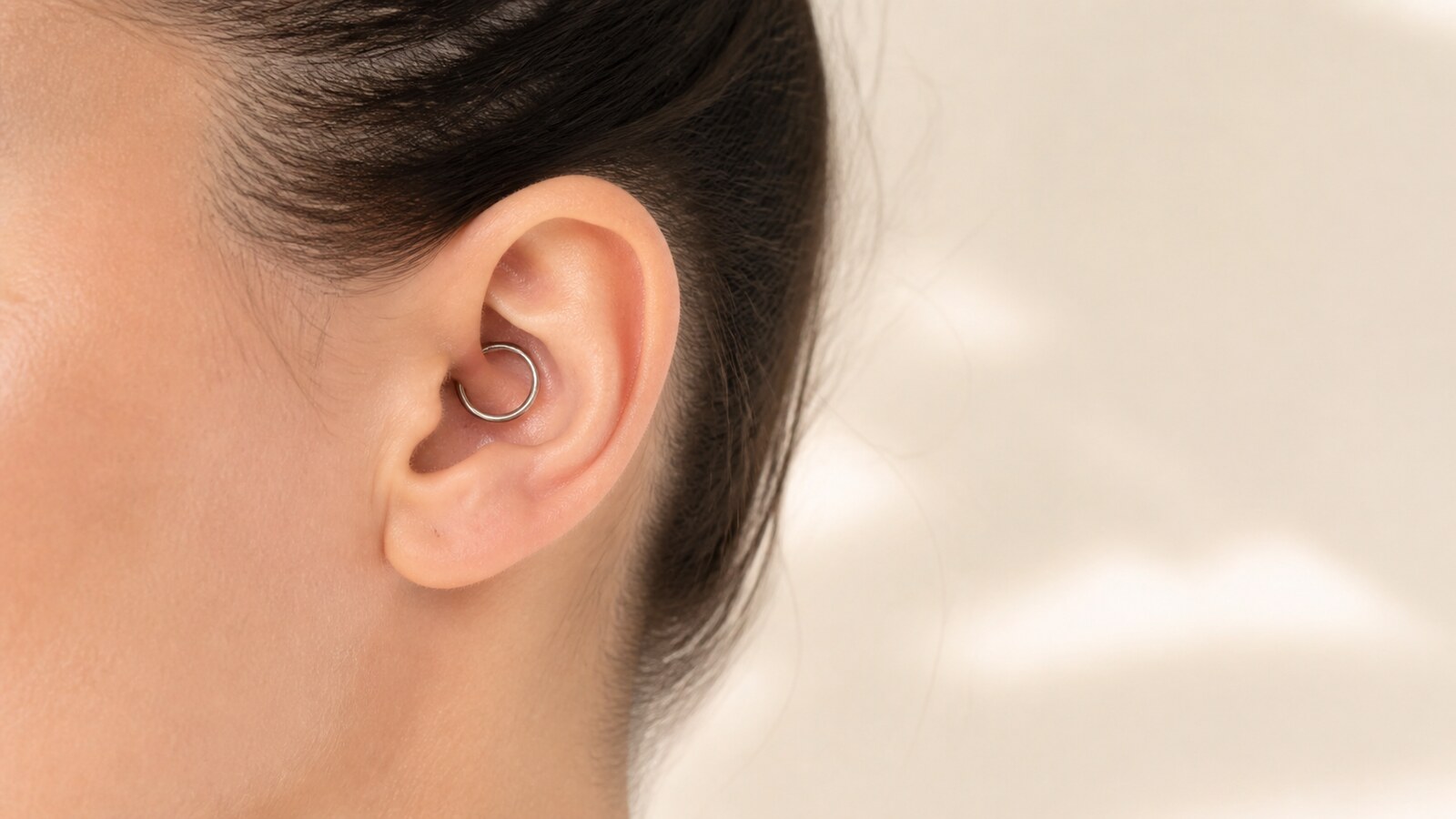 Adult ear with a single titanium ring placed through the daith fold