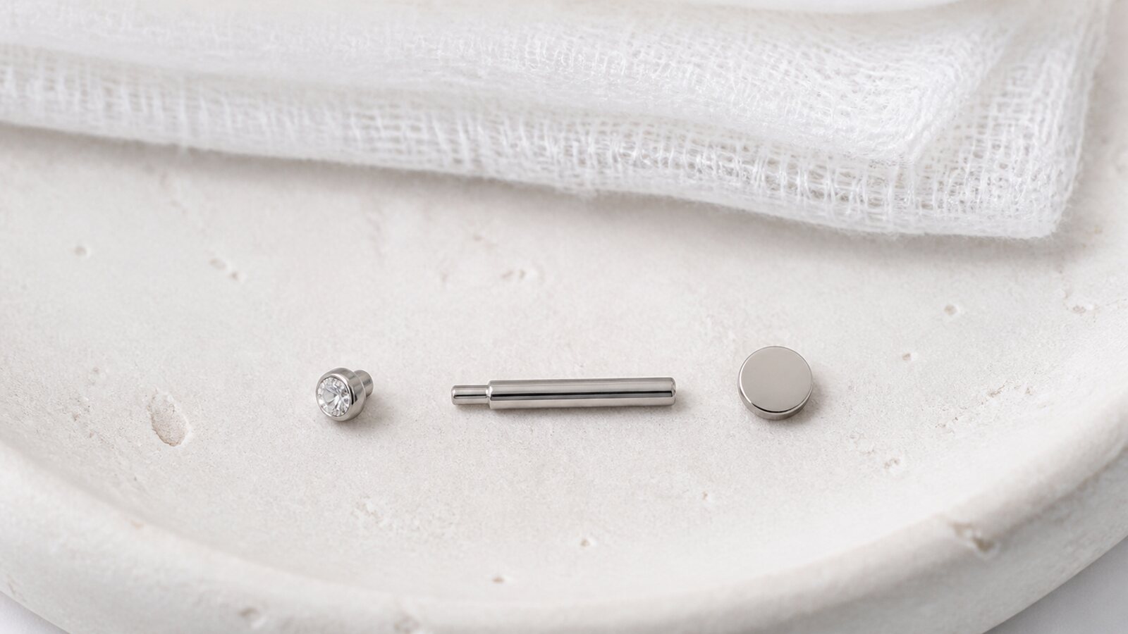 Threadless titanium flat-back labret shown as a front, smooth post, and flat disc back