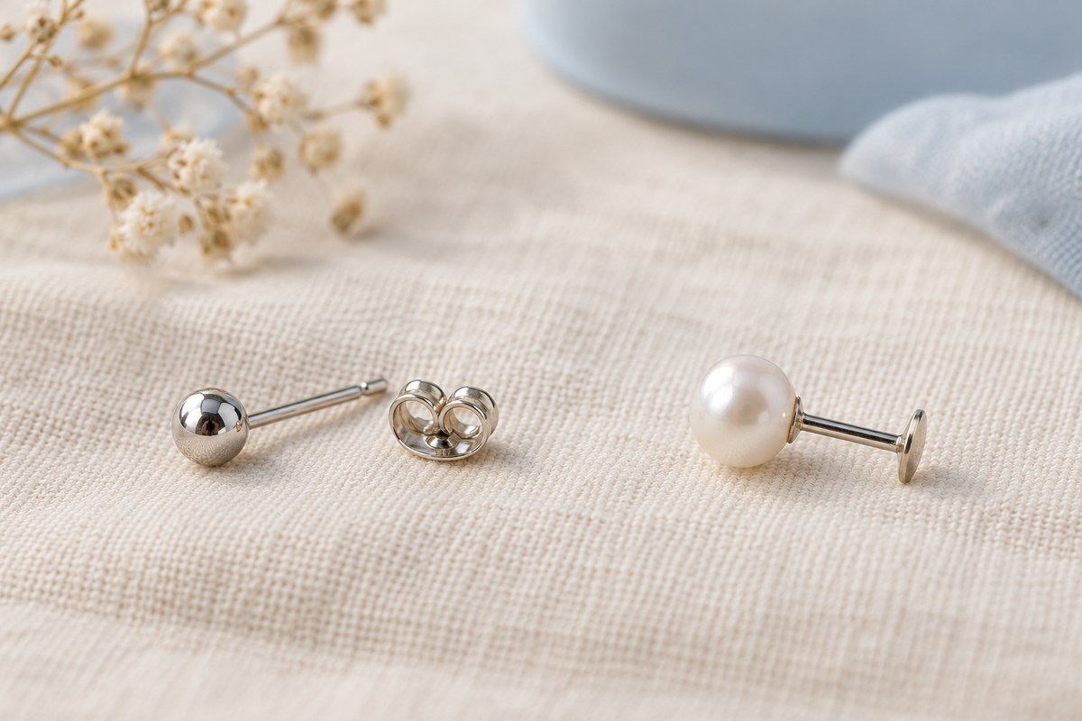 A ball stud with a separate butterfly back beside an assembled pearl flat-back stud.