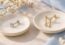A straight crystal flat-back stud and a curved chain-drop earring on separate dishes.