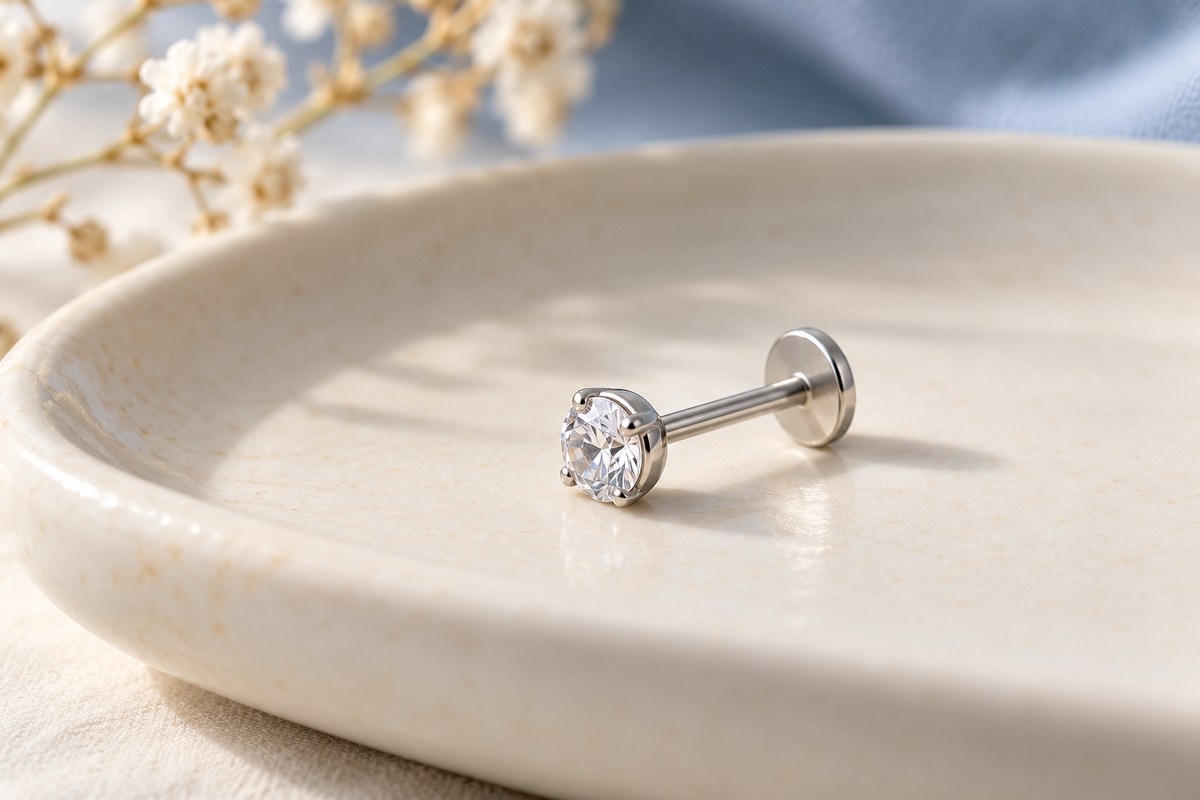 A crystal-front stud lying on its side with its straight post and flat disc visible.
