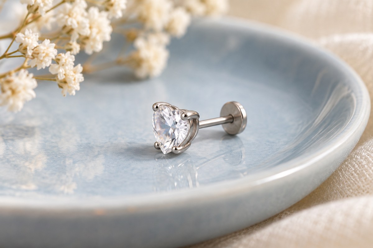 A clear faceted-stone flat-back stud lying on a pale blue dish.