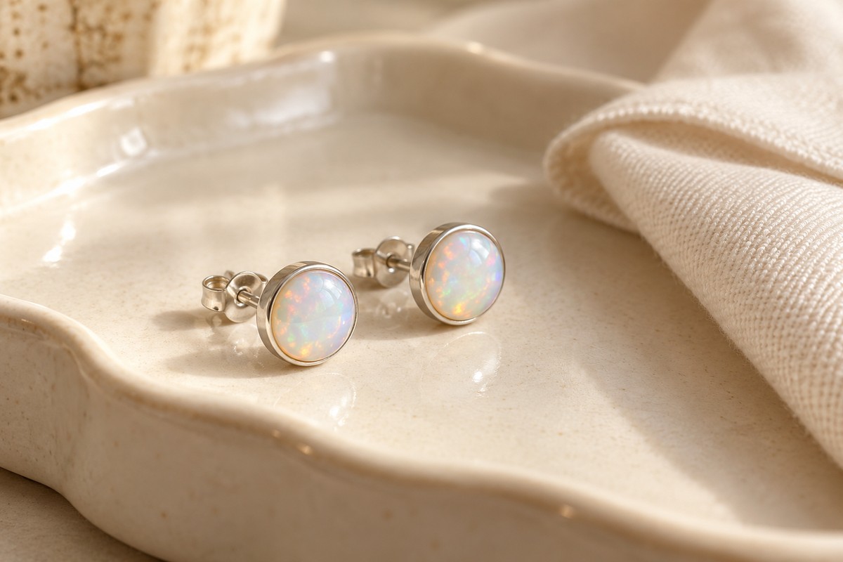 Milky iridescent stud earrings resting dry beside a soft cloth