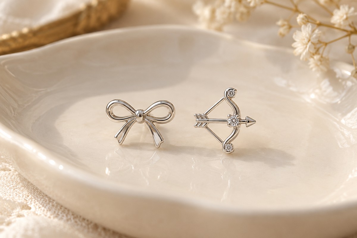 A ribbon-bow stud beside a bow-and-arrow motif